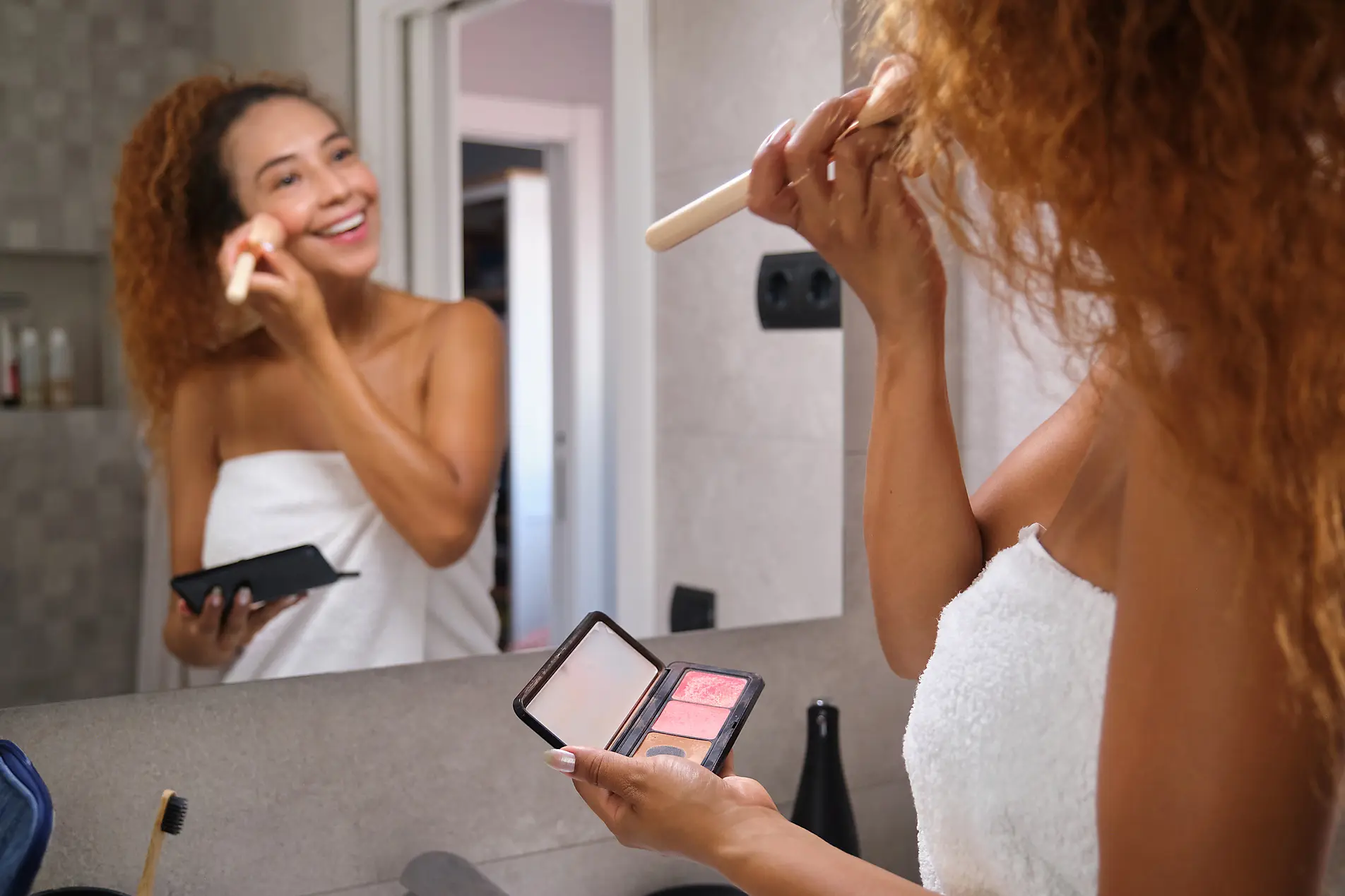 Woman putting on makeup in FU Apartment bathroom